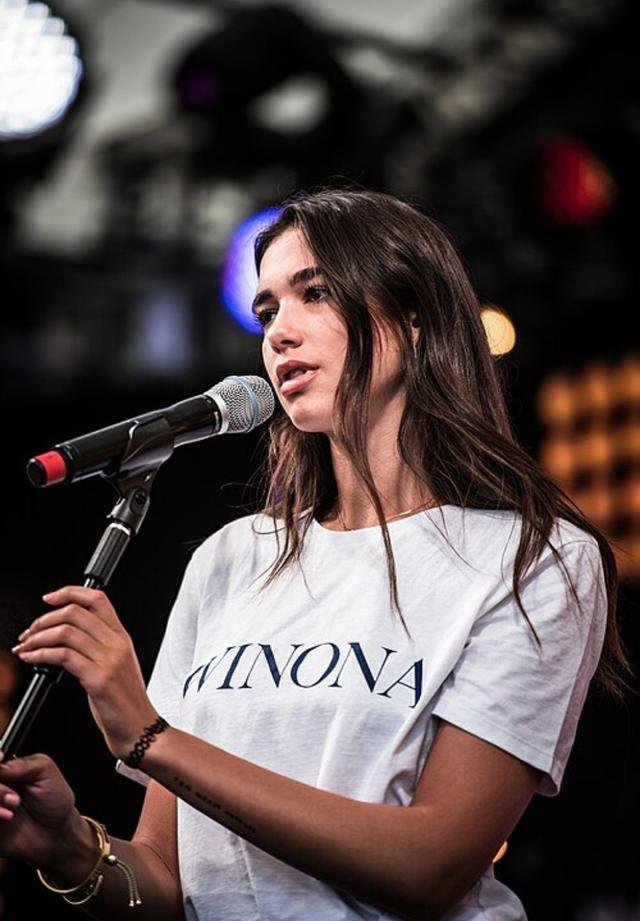 Dua Lipa singing at a microphone