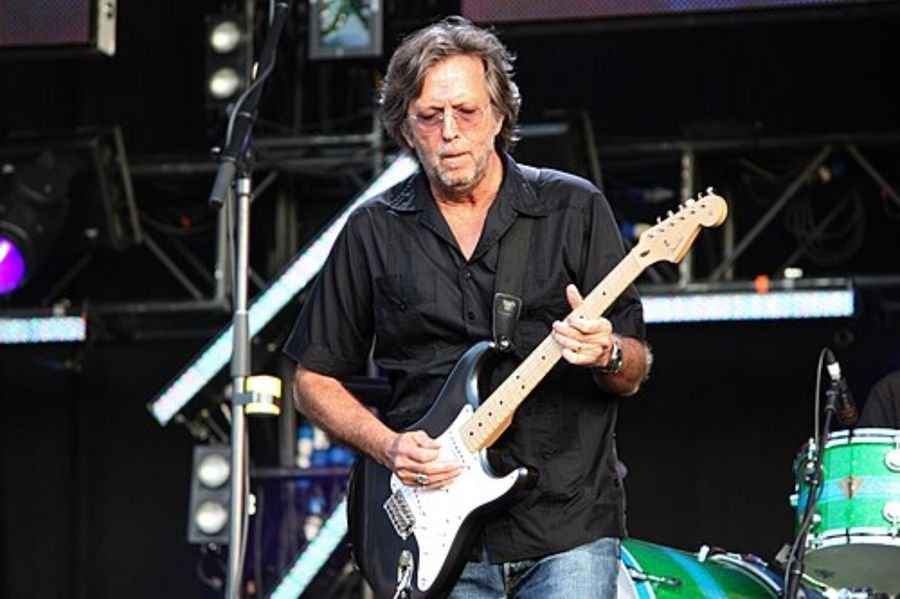 Musician in a black shirt playing an electric guitar on a festival stage, shown in the collaborations and evolution section