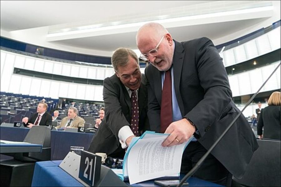 Two men reviewing documents in a legislative chamber, used in the political positions section