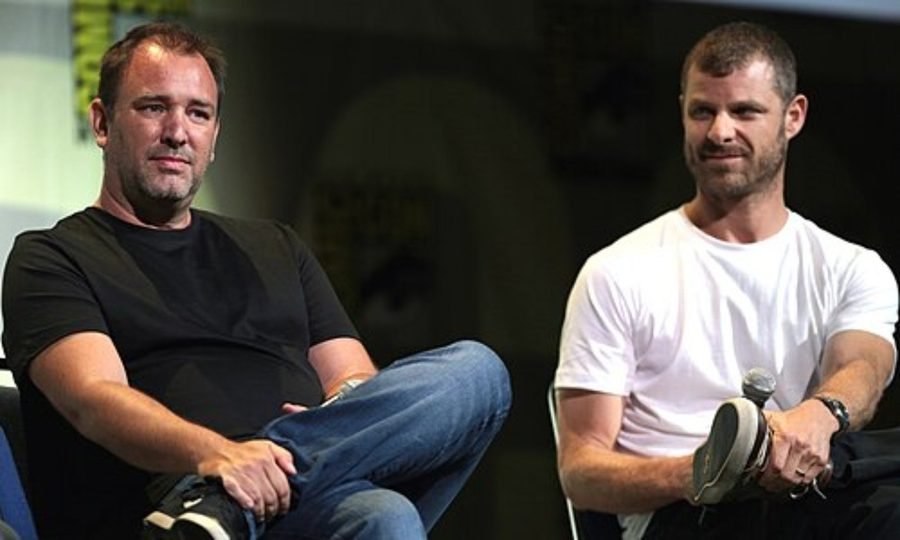 Two men seated and talking on a stage, shown in the Colorado origins section