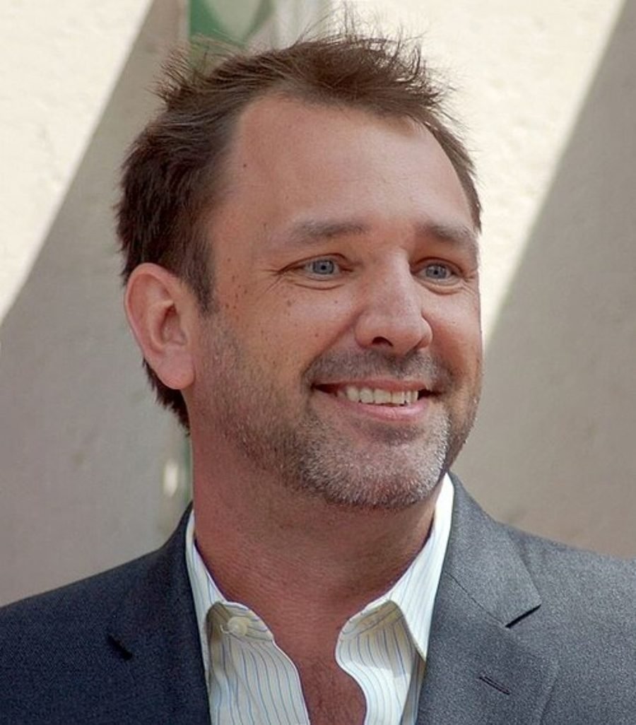 Smiling man in a grey blazer and open-collar shirt, shown in the section on his early films